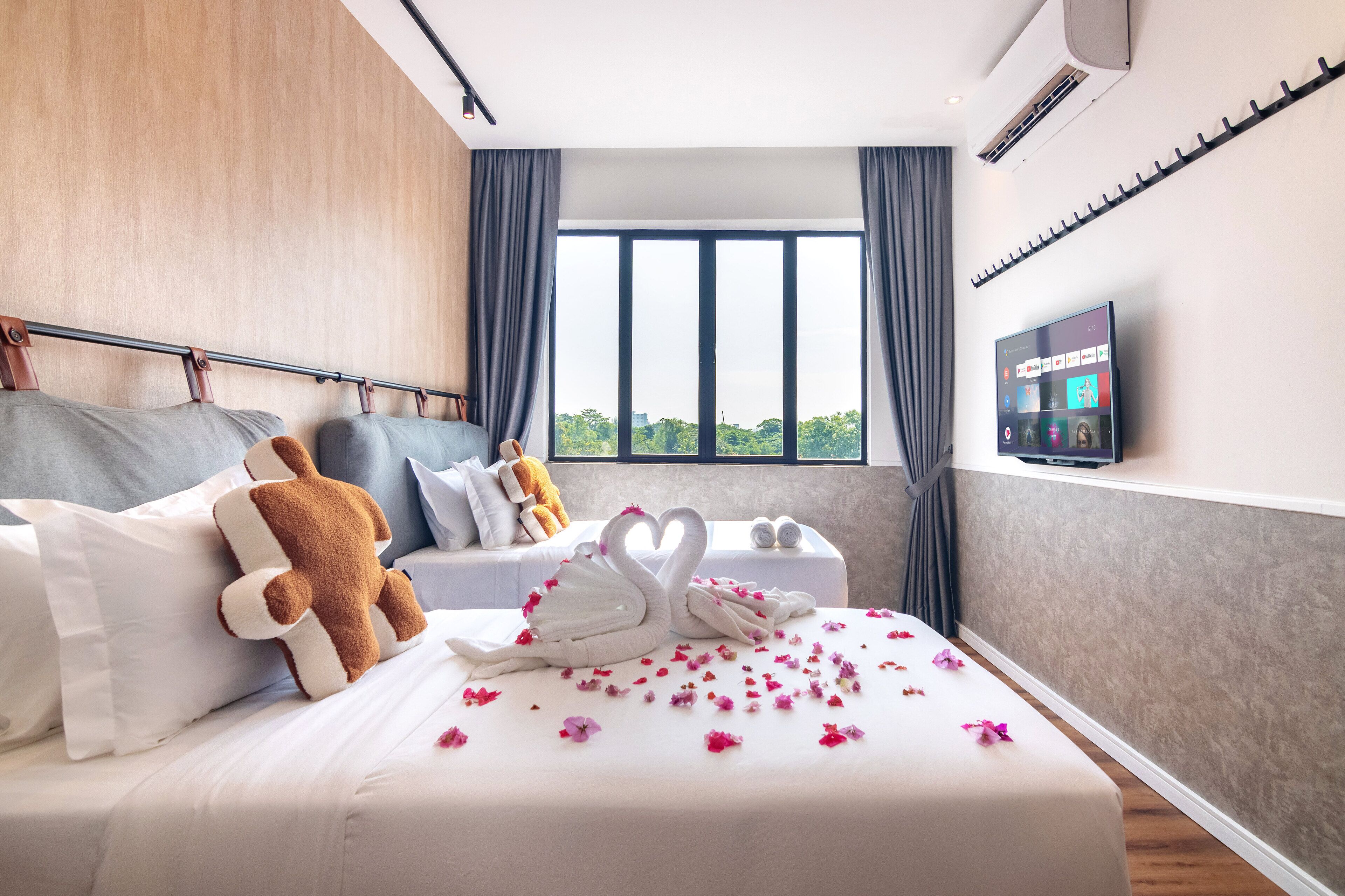 Habitación de hotel con cama, televisión, ventana con cortinas y vistas a zonas verdes.