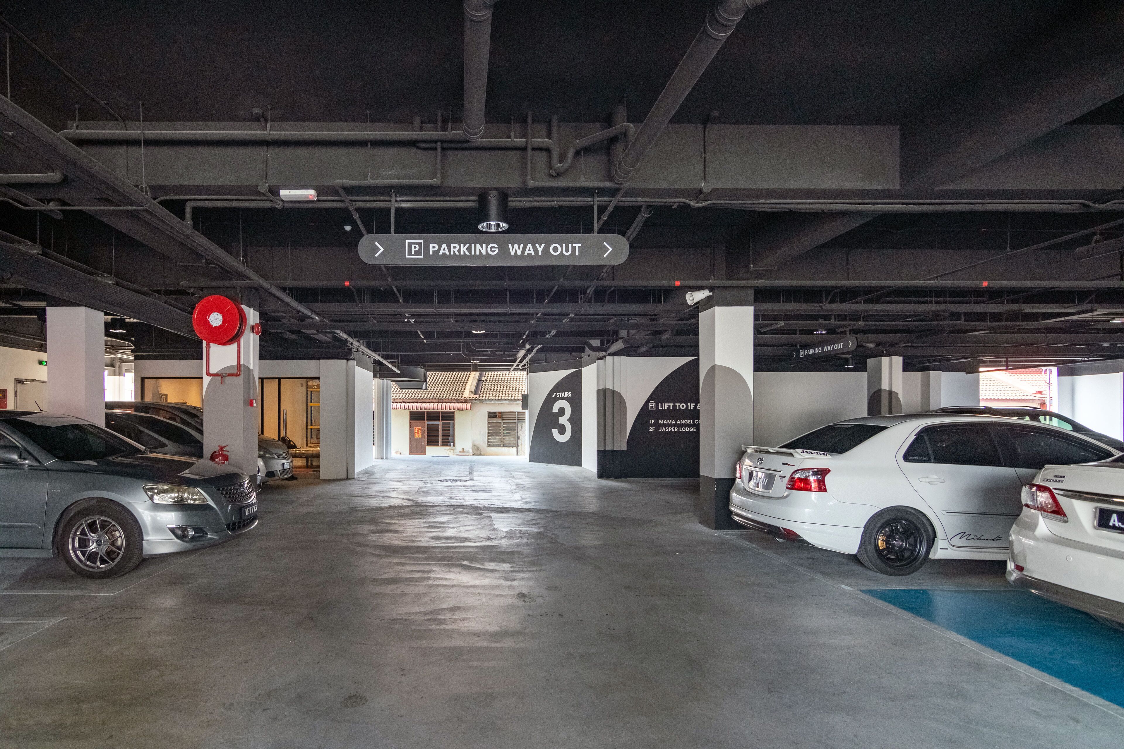 A parking garage with cars parked in designated spots, a sign indicating the parking way out, and a number 3 sign on the wall.