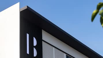 A modern building with a prominent 'B' logo on the facade, large windows, and a clear blue sky in the background.