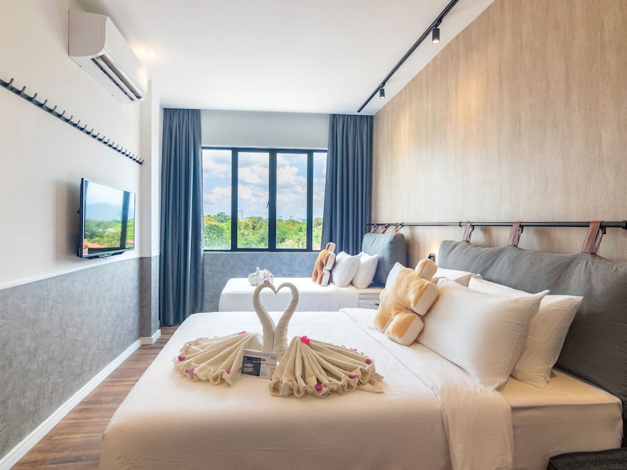 A hotel room with a bed, a TV, a large window, and a view of greenery.