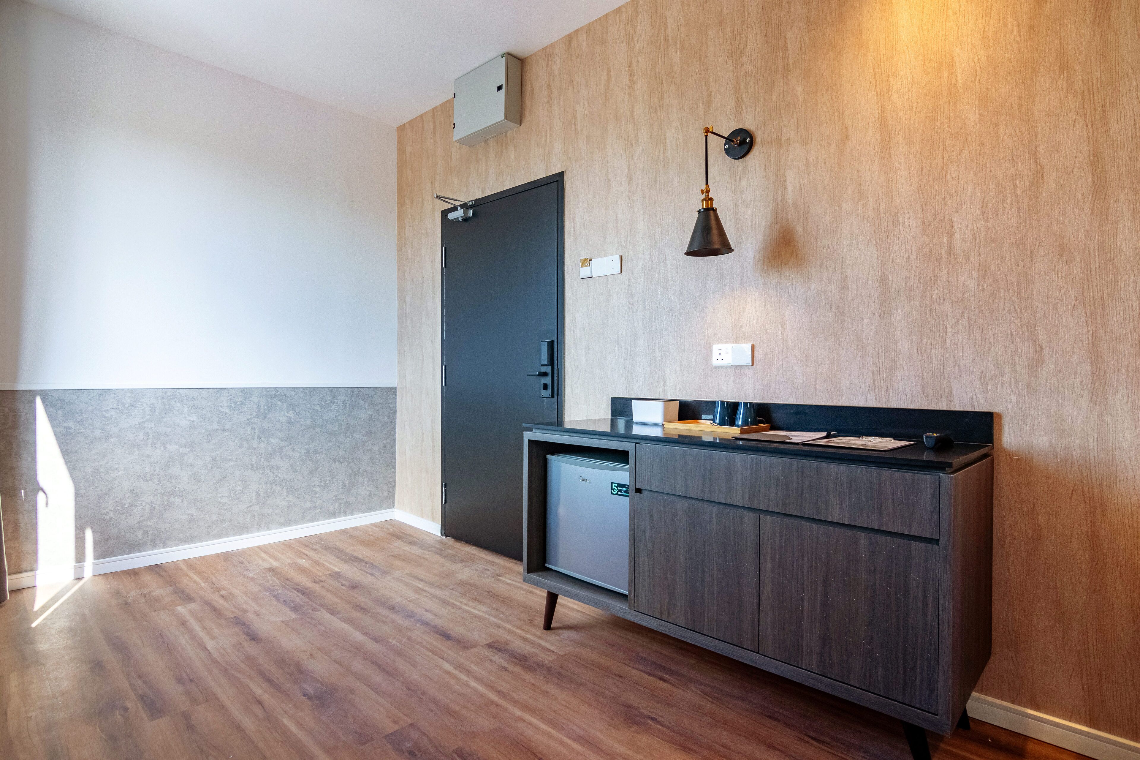 A modern kitchen with a dark wooden cabinet, a built-in dishwasher, and a wall-mounted light fixture.