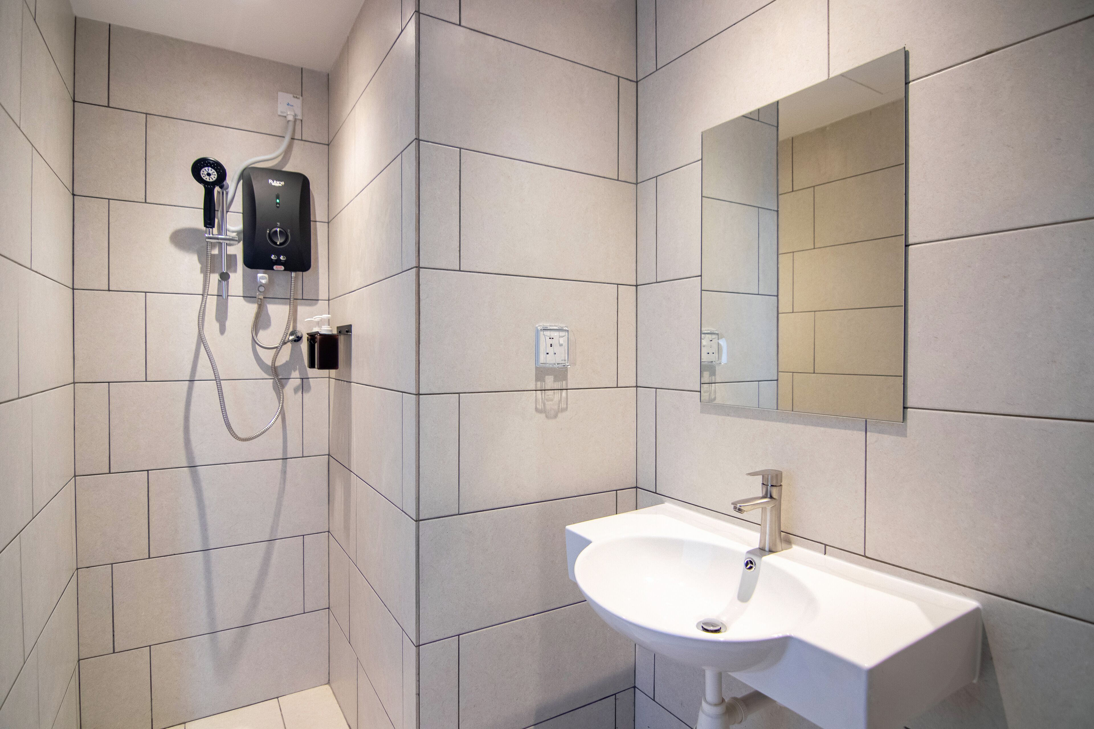 Un baño moderno con ducha, lavamanos y espejo.