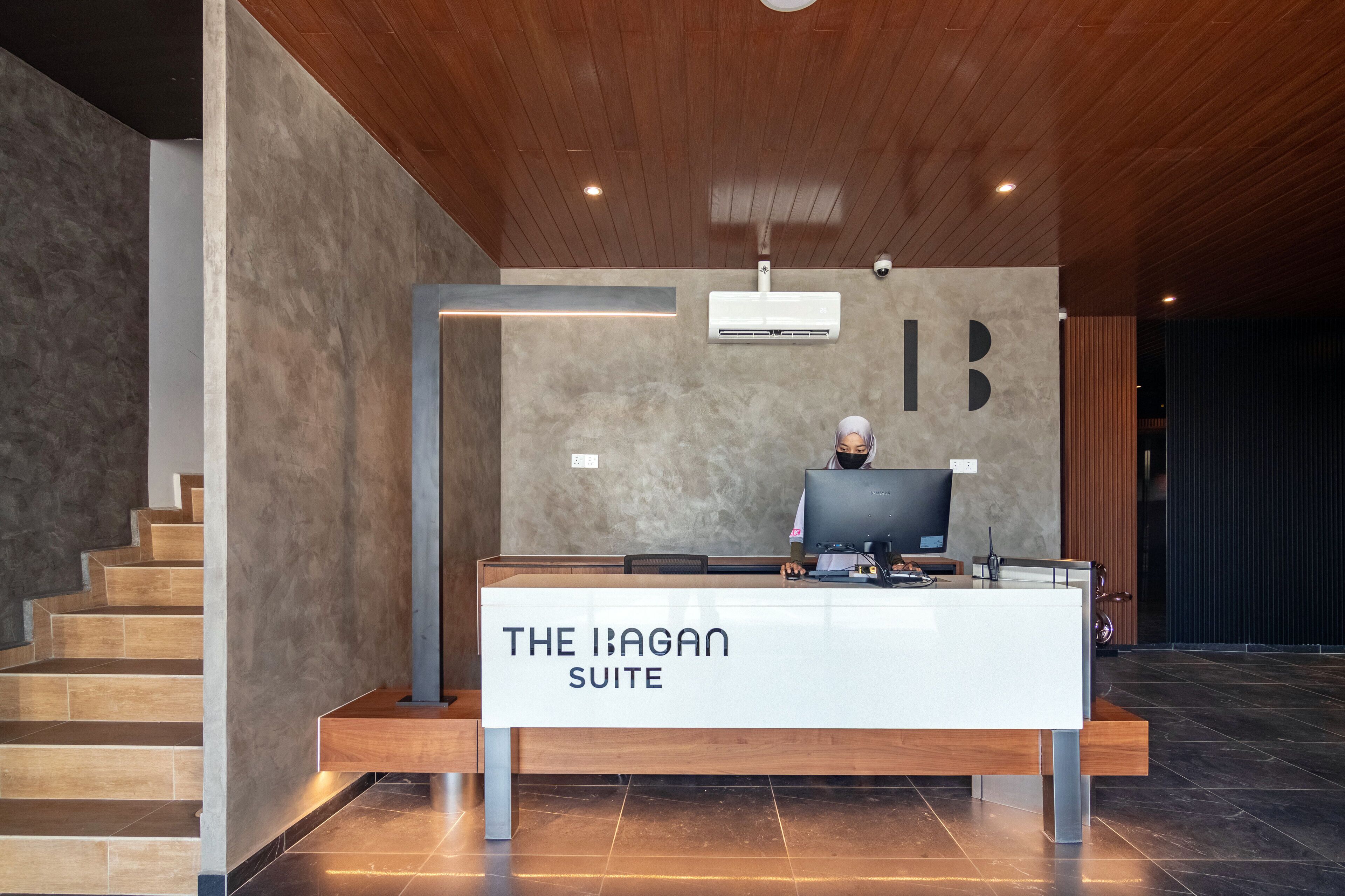 A reception desk labeled "The Ibagan Suite" with a modern design, wooden flooring, and a staircase to the left.