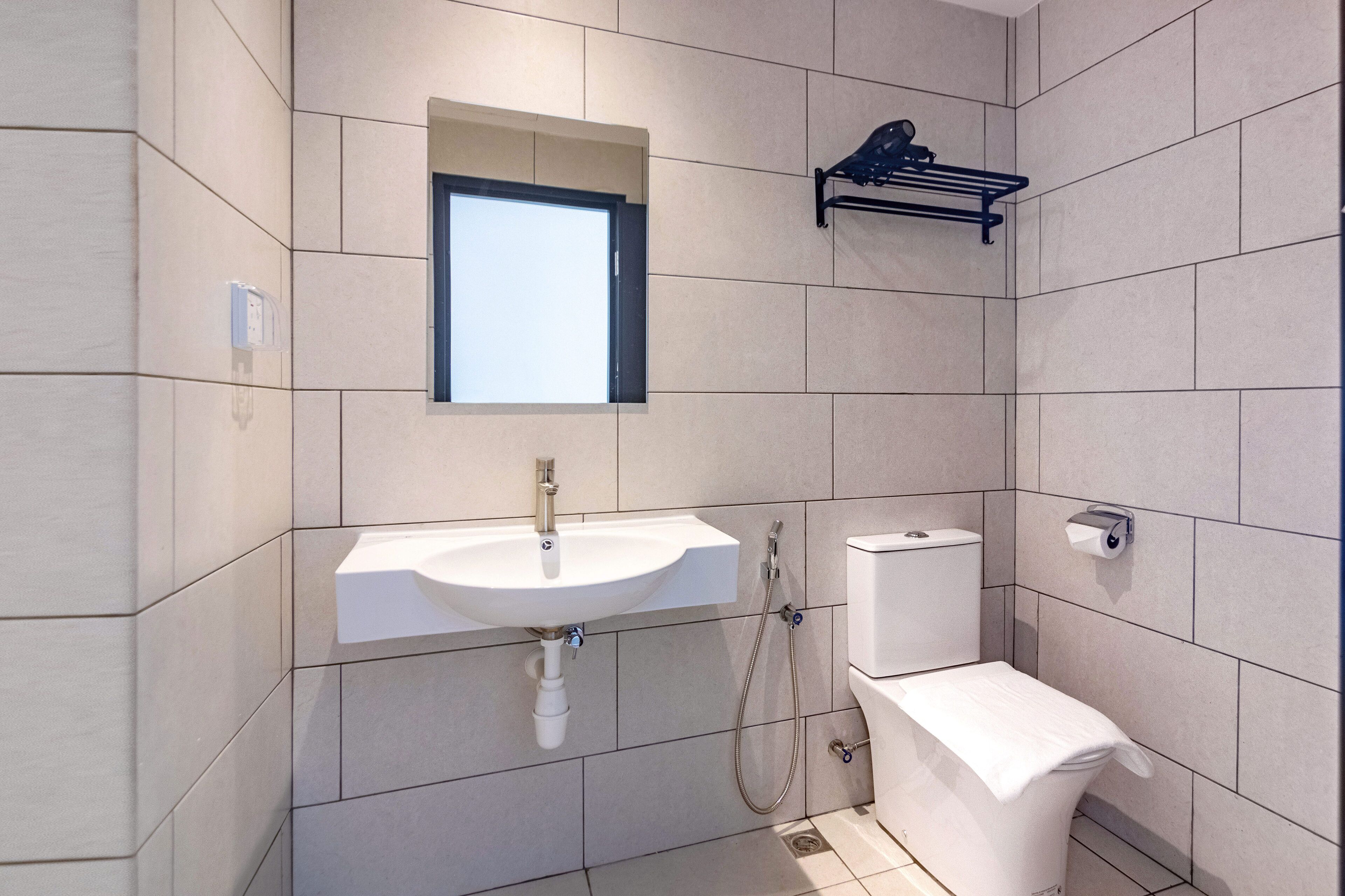 Un baño moderno con un lavamanos blanco, un inodoro y una ducha.