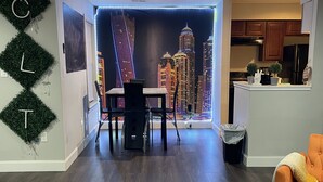 Ein modernes Wohnzimmer mit Stadtbild-Wandgemälde, einem Essbereich und einer Küche.