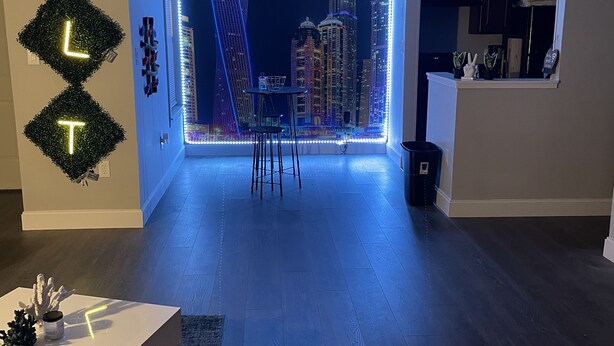 Ein modernes Wohnzimmer mit Blick auf die Stadt, ein Essbereich mit Tisch und Stühlen, und eine durch einen offenen Durchgang sichtbare Küche.