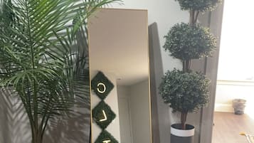 Reflect on serenity in this peaceful space, featuring a large mirror, lush greenery, and natural light.