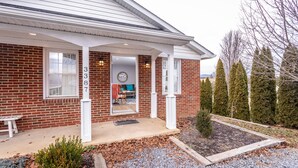 A brick house with a covered porch, numbered 387, and a small garden area with gravel and plants.