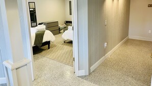 A hotel room with a bed, a dresser, a mirror, and a door leading to another room.