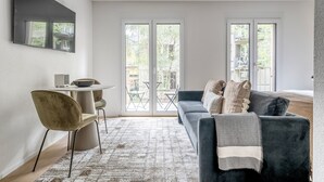 Un salon moderne avec un canapé, une petite table ronde et un téléviseur fixé au mur.