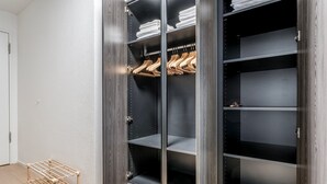 Un dressing avec de nombreuses étagères et un espace pour suspendre les vêtements, un porte-manteau en bois et un étendoir métallique.