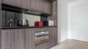 Une cuisine moderne avec des meubles de couleur bois foncé, un four encastré et un micro-ondes posé sur le plan de travail.