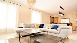 A modern living room with a sectional sofa, a glass coffee table, and a dining area with a table and chairs.