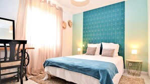 A bedroom with a bed, a desk, and a chair.