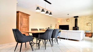 A modern kitchen with a dining area, featuring a wooden cabinet, a dining table with chairs, and pendant lighting.