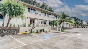 A hotel with a parking lot, a covered walkway, and a building with multiple floors and balconies. - Unit 25 Waena Inn - Maui Private Suite (Wailuku)