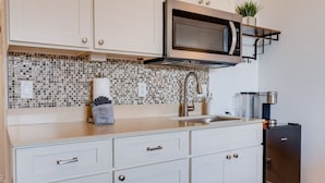 A modern kitchen with white cabinetry, a stainless steel microwave, and a coffee machine. - Unit 25 Waena Inn - Maui Private Suite (Wailuku)