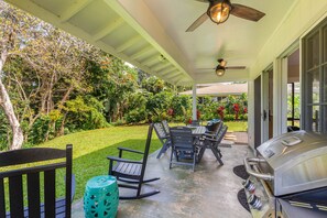 Un patio exterior con una parrilla, asientos y un ventilador de techo.
