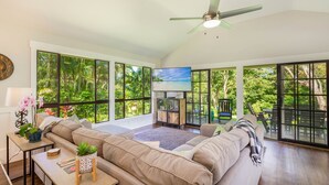 A spacious living room with a large sofa, a television, and a ceiling fan. - Princeville Private 3 bed 2 bath w/AC (Princeville)