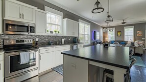 A modern kitchen with white cabinets, a large island, stainless steel appliances, and a dining area with a table and chairs.