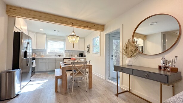 A modern kitchen with a central island, stainless steel appliances, and a dining area with a wooden table and chairs.