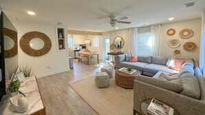 A modern living room with a grey sofa, a coffee table, and a dining area with a wooden table and chairs.