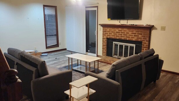 Ein Wohnzimmer mit Kamin, einem darüber montierten Fernseher und einer Sofagarnitur.