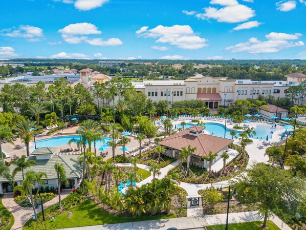 A resort with multiple swimming pools, palm trees, and a large building with a red-tiled roof.