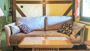 Une pièce chaleureuse avec un canapé marron, deux coussins à motifs floraux et une table basse en osier.