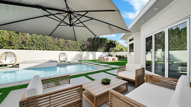 A modern outdoor pool area with a wooden deck, lounge chairs, and a large umbrella. - Ultra modern contemporary Luxe (Palm Springs)