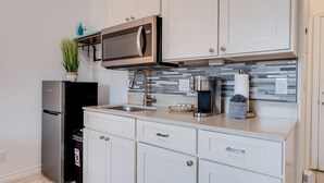 A modern kitchen with white cabinets, a stainless steel refrigerator, a built-in microwave, a coffee maker, and a sink. - Unit 26 Waena Inn - Maui Private Suite (Wailuku)