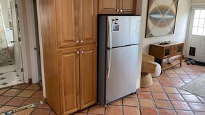 A kitchen with wooden cabinets, a refrigerator, and a tiled floor. - Beach House, 1 block to beach, walk to town, great outdoor space (Cayucos)