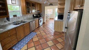 A kitchen with wooden cabinets, a stainless steel refrigerator, a built-in oven, and a tiled floor. - Beach House, 1 block to beach, walk to town, great outdoor space (Cayucos)