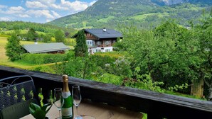Eine Holzterrasse mit einer Weinflasche, Gläsern und einem Blumentopf.