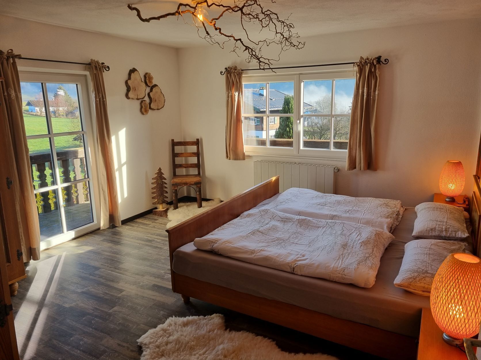 Ein Schlafzimmer mit einem großen Bett, zwei Fenstern, einem Sessel und einer Lampe.