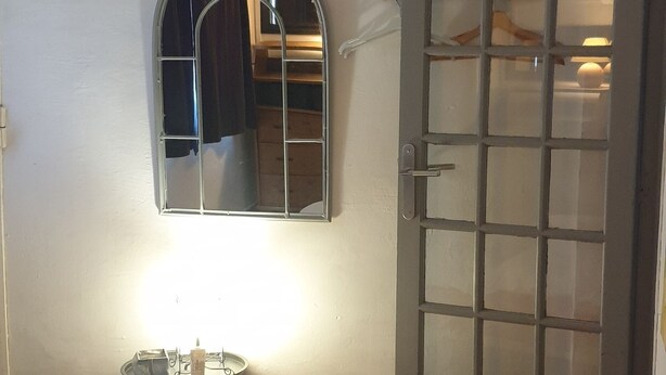 Ein Schlafzimmer mit Bett, Nachttisch, Spiegel und Kleiderschrank mit Glastür.