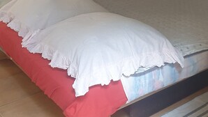 Ein Schlafzimmer mit einem Bett, Kissen, einem farbenfrohen abstrakten Gemälde und einem Streifen Teppich.