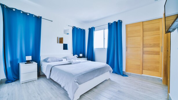 Un dormitorio moderno con cama, mesitas de noche y un armario.