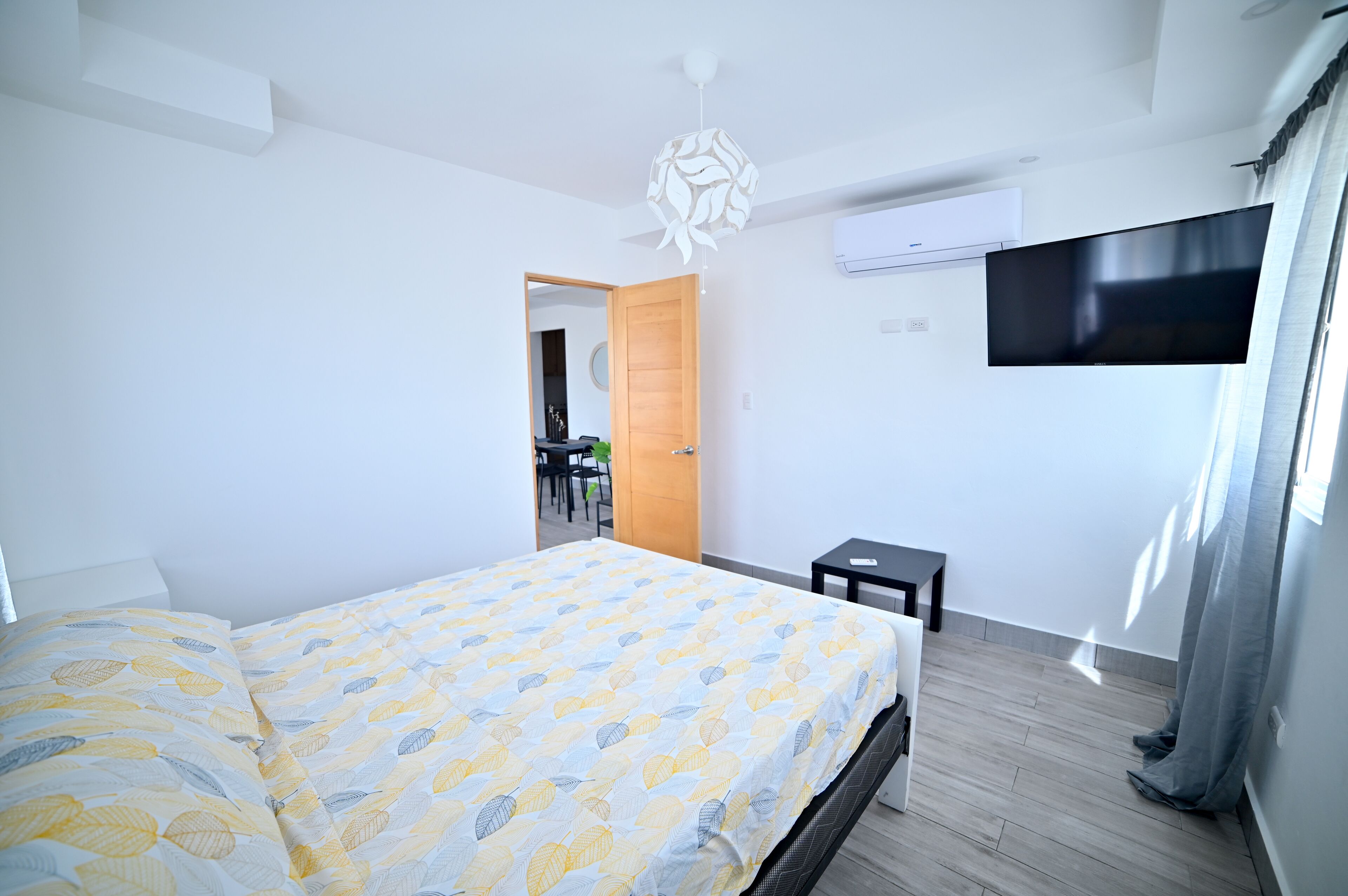 Um quarto moderno com uma cama, uma televisão e uma mesinha.