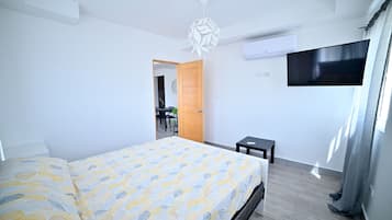 Um quarto moderno com uma cama, uma televisão e uma mesinha.