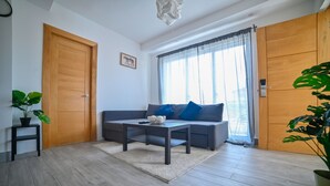 Una sala moderna con un sofá gris, una mesa de centro y una planta en maceta.
