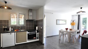 A modern kitchen with a dishwasher, oven, and sink. There is a dining area with a table and chairs.
