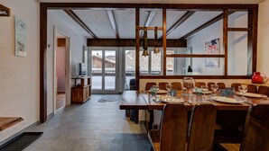 A dining area with a wooden table set for four, a television, and a view of a snowy mountain. - Appartement Savoleyres 10 - La Tzoumaz, 4 Vallees (La Tzoumaz)