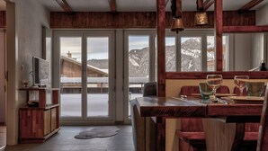 A wooden interior with a dining area, large windows, and a view of snowy mountains. - Appartement Savoleyres 10 - La Tzoumaz, 4 Vallees (La Tzoumaz)