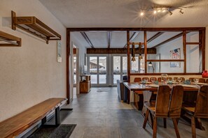 Un espace repas avec des meubles en bois, un banc et une vue dégagée grâce à de grandes fenêtres.