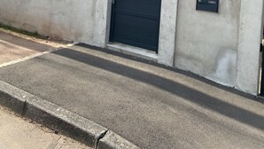 A two-story house with a beige exterior, a black gate, and a small staircase leading to the front door. - Le Mathiez (Dijon)