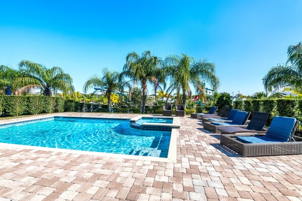 A swimming pool with lounge chairs and palm trees.