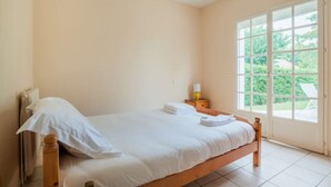 Une chambre à coucher avec un lit, une table de chevet, une fenêtre et une vue sur la verdure.