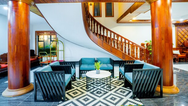 A lobby with a curved staircase, wooden columns, and blue seating area. - Blanc Smith Hotel  (Siem Reap)