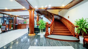 A spacious lobby with a marble floor, a wooden staircase, and a reception area with a counter and chairs. - Blanc Smith Hotel  (Siem Reap)